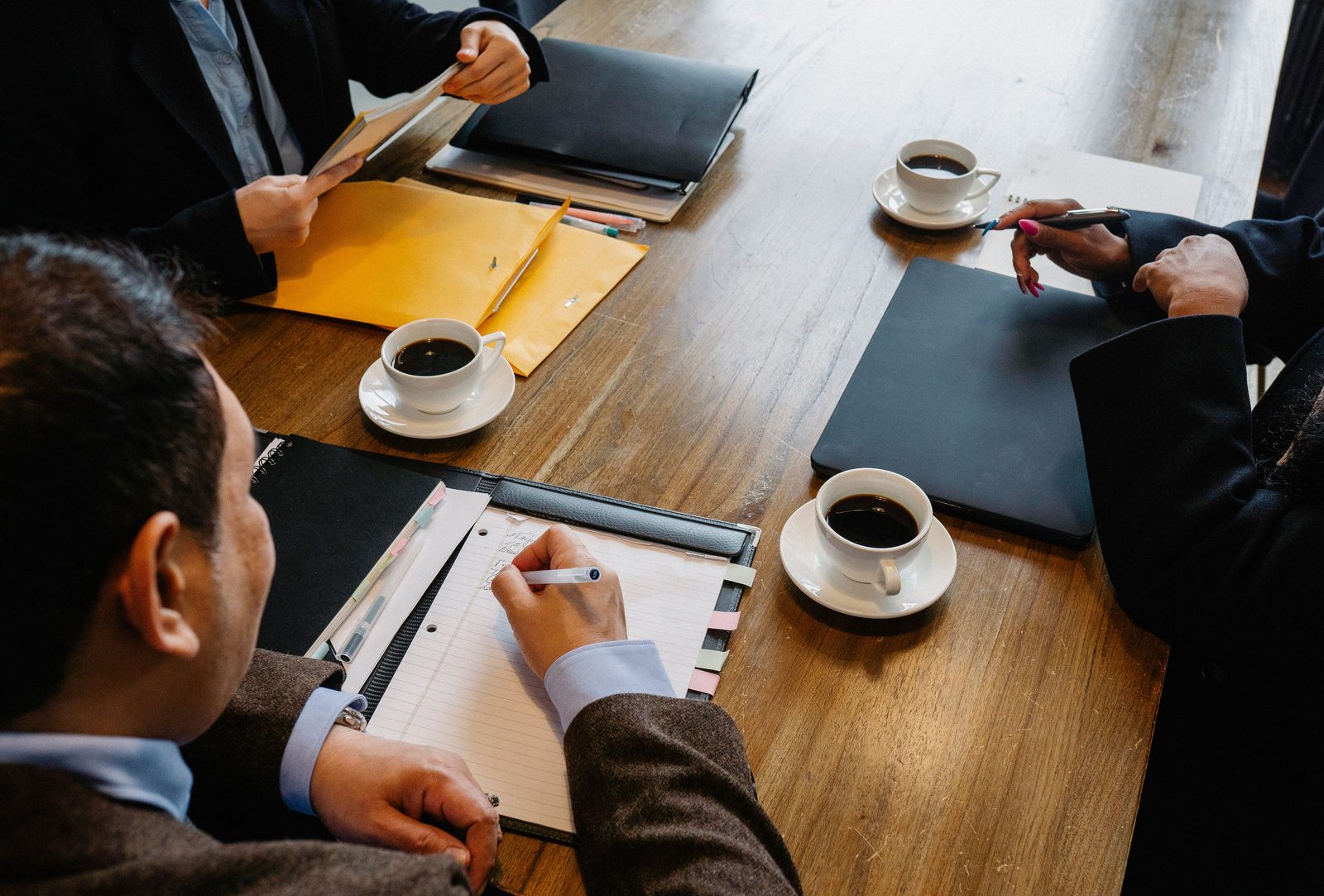 Business meeting with notes, coffee and folders on a table